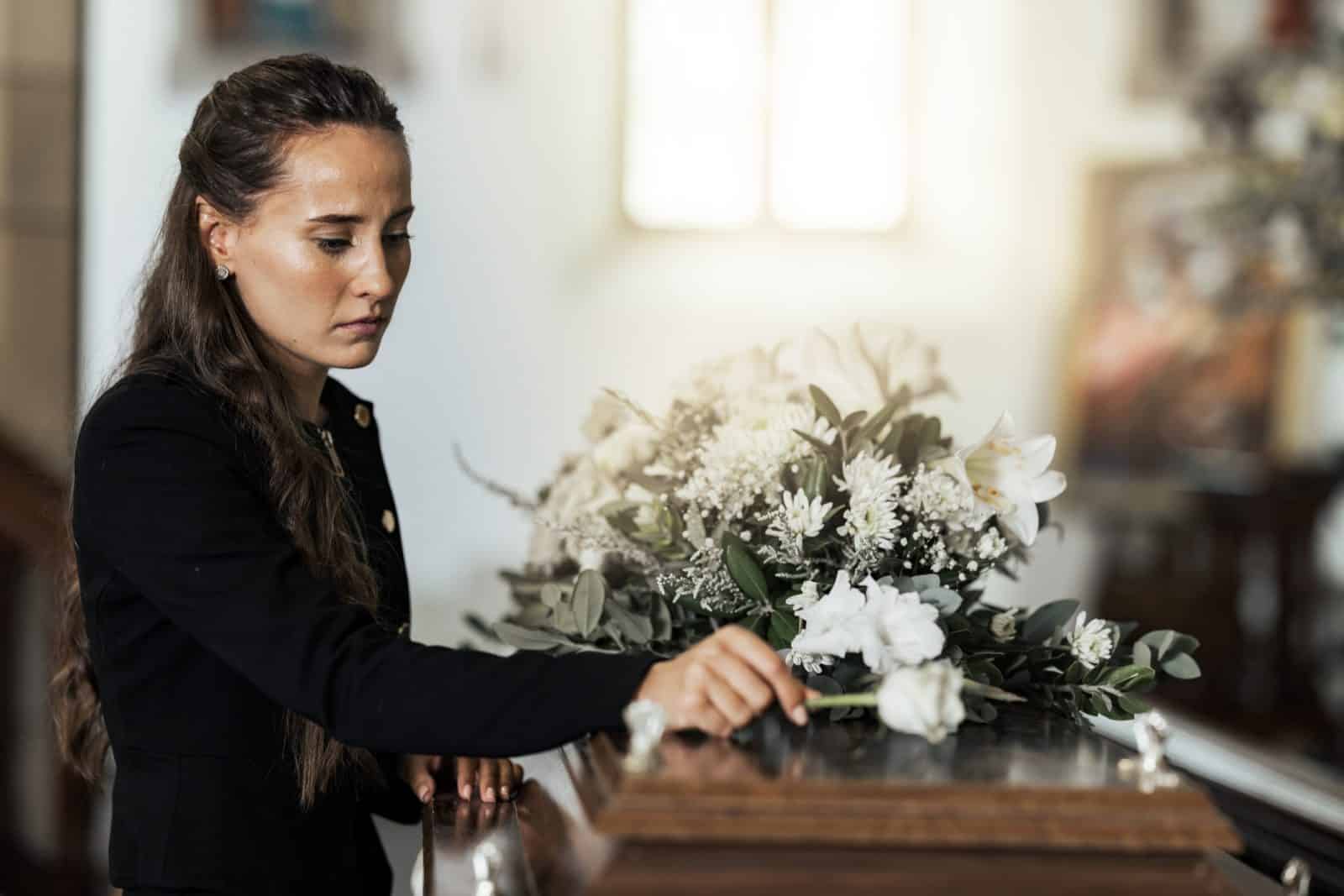 A woman lays flowers on the casket of a loved one who died a wrongful death.