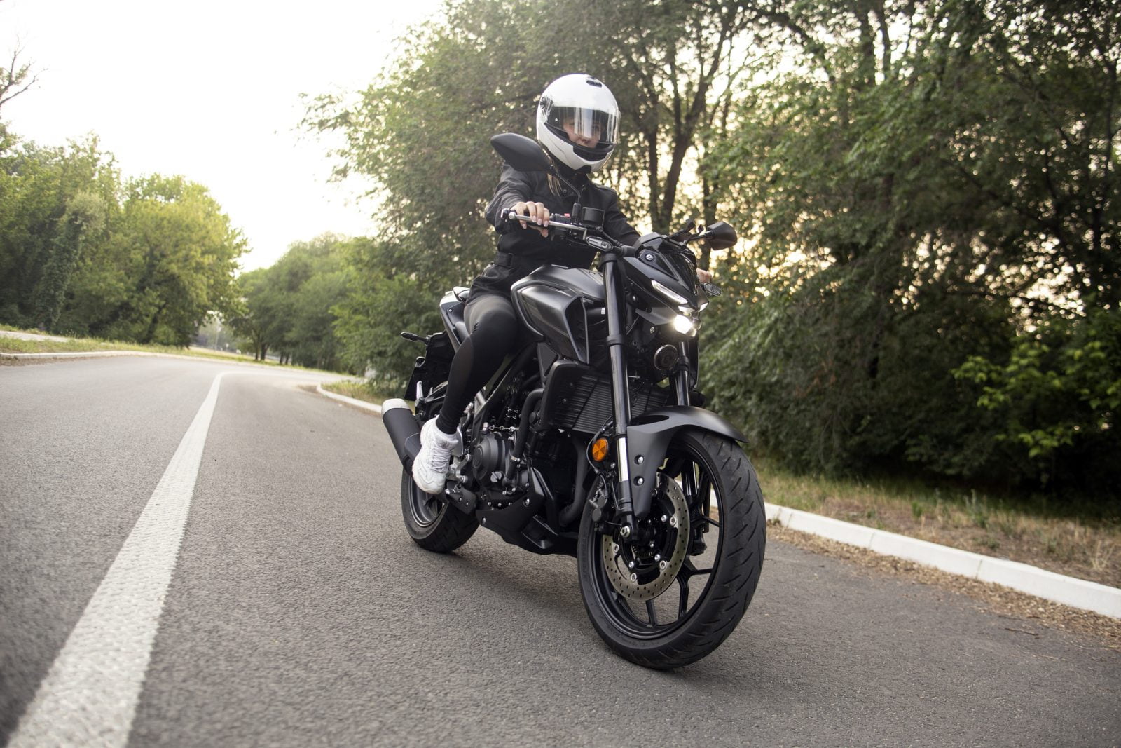 A motorcycle rider in full gear is seen riding along the road.