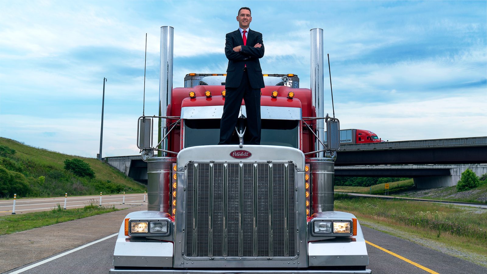 Attorney James Beardsley standing on top of a big truck, smiling with his arms crossed.